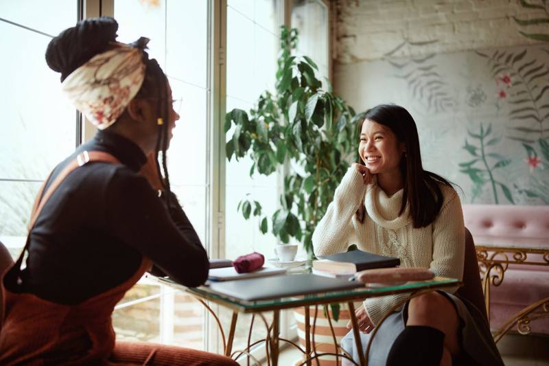 Two friends talking at a cafe window
