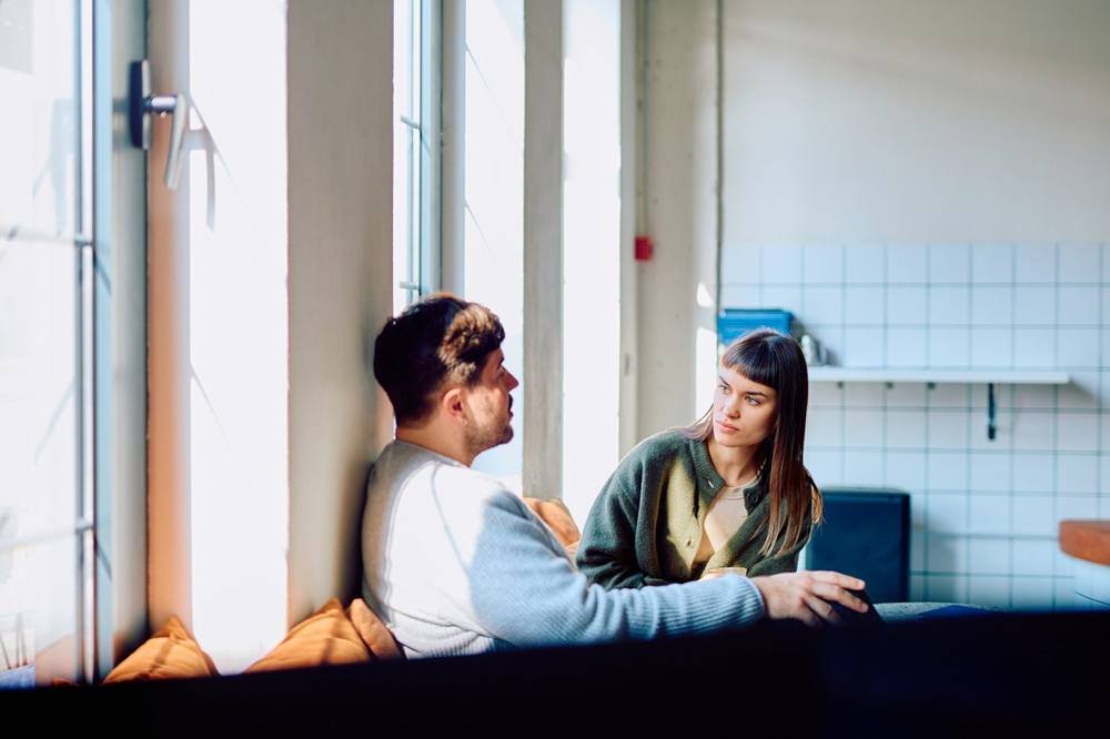 Two people talking on a sunny window seat